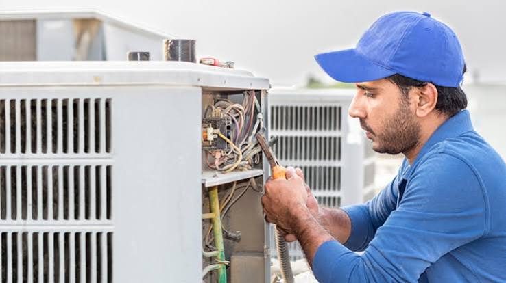 HVAC technician working on an open air conditioner electrical panel