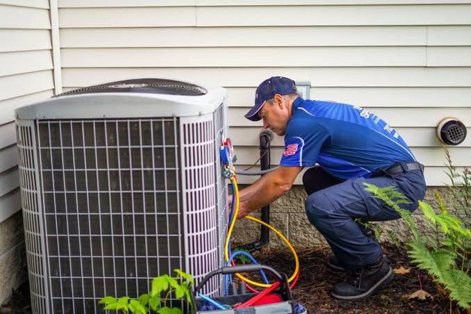 HVAC technician connecting gauges on an outdoor air conditioner