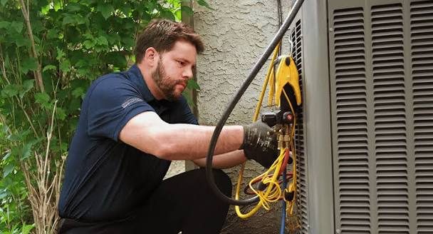 Technician using recovery hoses on an outdoor condenser