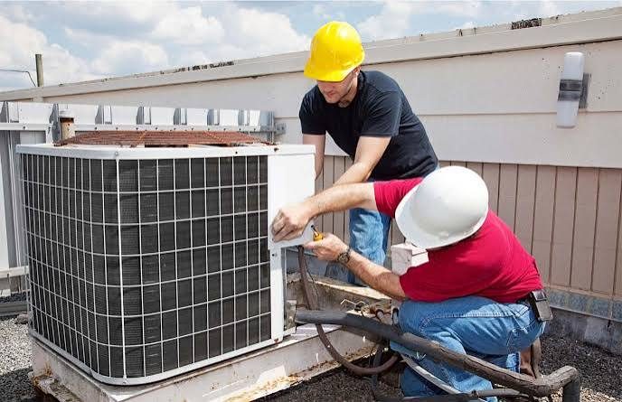 Two workers servicing a rooftop air conditioning condenser
