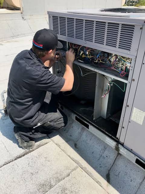 Technician working inside an open rooftop HVAC unit